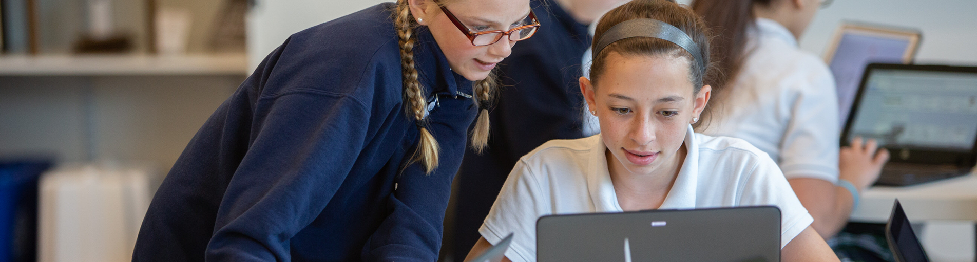 students in a class looking at one laptop